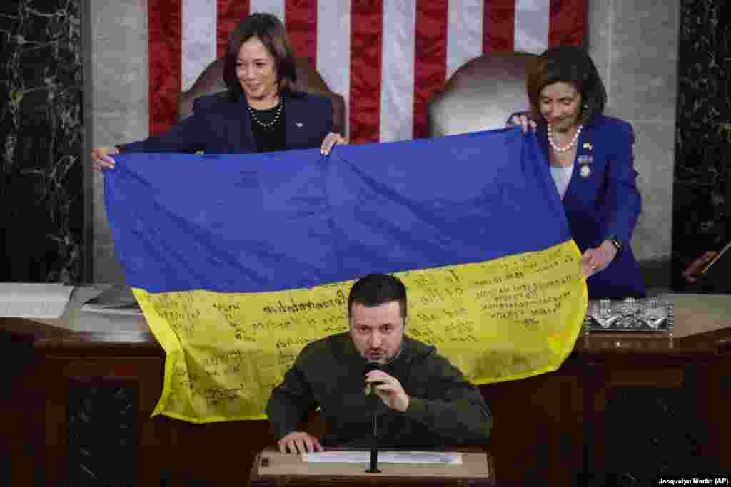 U.S. Vice President Kamala Harris (left) and then-House Speaker Nancy Pelosi react as Ukrainian President Volodymyr Zelenskiy presents lawmakers with a Ukrainian flag autographed by frontline troops in Bakhmut as he addresses a joint session of Congress in Washington on December 21, 2022.