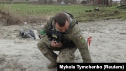 Военный сапер поднимает неразорвавшуюся часть кассетной бомбы