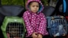 A girl sits between pet carriers as civilians evacuated from the Russian-controlled city of Kherson wait to board a bus heading to Crimea on October 22.