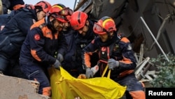 Куткаруучулар урандылардын астынан кишилерди алып чыгууда.