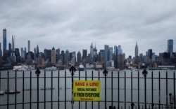 Табличка, напоминающая о важности соблюдения социальной дистанции, на заднем плане — вид на Манхэттен, Нью-Йорк, 3 апреля 2020 года.