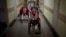 Followed by their mother Natasha, Yarik Stepanenko, 11, pushes his twin sister Yana's wheelchair along a corridor of a public hospital in Lviv on May 12. They were injured on April 8 when a Russian missile struck the train station in the eastern city of Kramatorsk.
