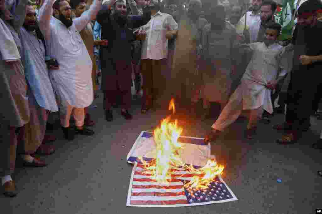 Иранга сокку урулганын айыптаган акциянын катышуучулары АКШнын желегин өрттөшүүдө. Пешавар, Пакистан.