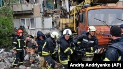 Halas edijiler gündogar Donetsk sebitindäki Bahmut şäherinde rus zarbalary bilen ýykylan köp gatly binanyň harabalygynda bir asuda raýatyň jesedini göterip barýarlar. 18-nji maý. 