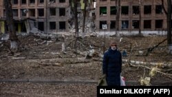 Жінка на тлі зруйнованої російськими обстрілами будівлі у Василькові Київської області, 27 лютого 2022 року