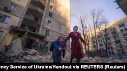 Russiýanyň hüjümi netijesinde Kiýewiň ýaşaýyş jaýlarynyň birinden gaçyp barýan parahat ilat. 