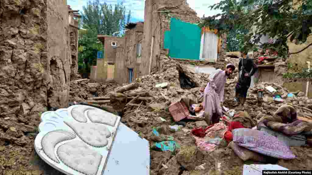 دو تن از باشنده های ولسوالی خوشی لوگر که خانۀ شان در اثر سیلاب ویران شده در حال بیرون کردن برخی از اسباب منزل شان از آوار اند