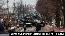2002-nji ýylyň 1-nji martynda Kiýewiň etegindäki Buça etrabynda asuda adamlar ýok edilen rus bronetehnikasynyň hataryna seredýärler.