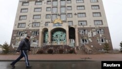 A man walks in Almaty, Kazakstan, walks past the office building of the Nur Otan ruling party, which was damaged during mass protests triggered by a fuel price increase in January. 
