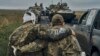 A Ukrainian soldier helps a wounded comrade on a road in recently liberated territory in the Kharkiv region on September 12.