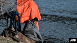 Түркия менен Грекиянын чек арасында кийимин кургатып отурган оогандык качкын.