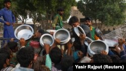 People who were displaced during severe flooding receive food handouts at an aid camp in Sehwan, Pakistan, on September 11, 2022.