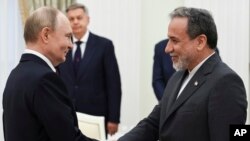 Vladimir Putin Kremldə danışıqlardan əvvəl Abbas Ərağçini salamlayır.