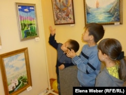 Дети рассматривают на выставке картины юных художников. Караганда, 2 июля 2013 года.