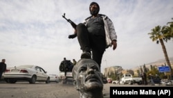 Սիրիա - Զինյալ ապստամբը Դամասկոսում ոտքը դրել է երկրի նախկին նախագահի և գործող նախագահ Բաշար Ասադի հոր՝ Հաֆեզ Ասադի հոր արձանի պոկված գլխին, 8-ը դեկտեմբերի, 2024թ.