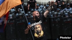 Armenia - An opposition supporter waves a Karabakh flag outside a goverment building guarded by riot police, May 31, 2022.