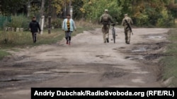 Українські військові йдуть з позицій до магазину по вулиці Миру у фронтовому селищі Кримське, вересень 2021 року