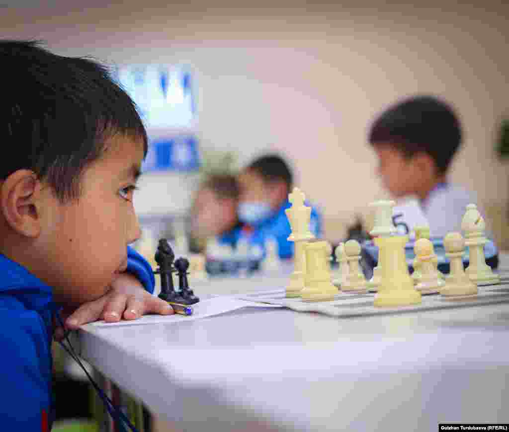 Сегиз жаштагы балдар арасында мелдешке катышып жаткан шахматчы.