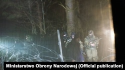 Беларускія вайскоўцы суправаджаюць мігрантаў падчас спробы прарыву беларуска-польскай мяжы. 22 лістапада 2021