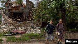 Жінки йдуть повз зруйнований обстрілами будинок на Миколаївщині, 16 вересня 2022 року