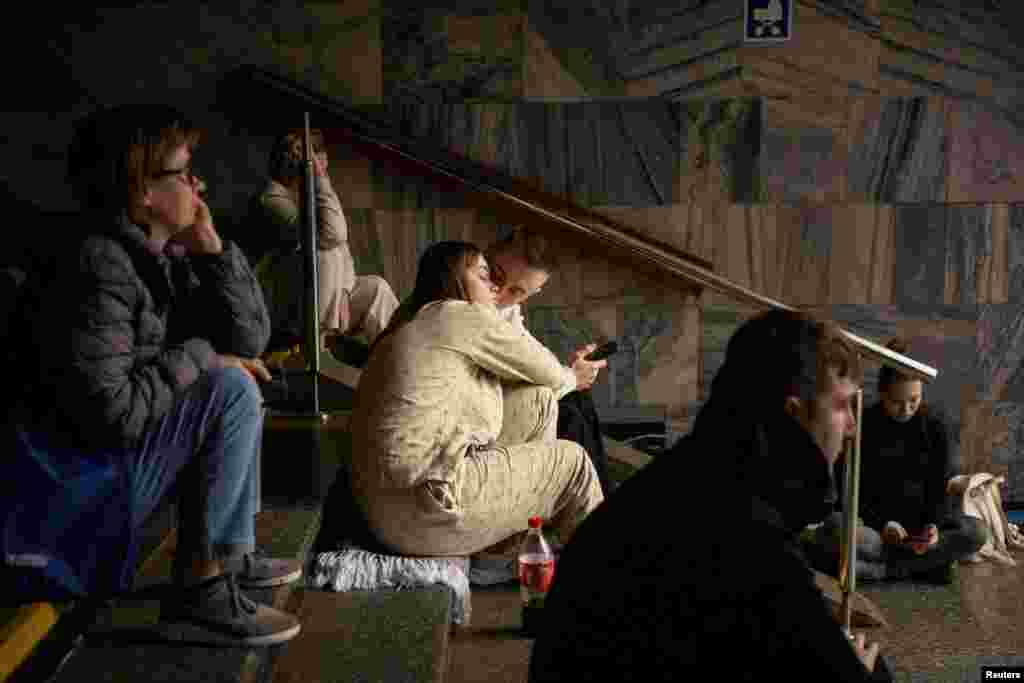 Орусиянын бомбасынан качкан кишилер Киевдеги метронун станциясында баш калкалап отурушат.