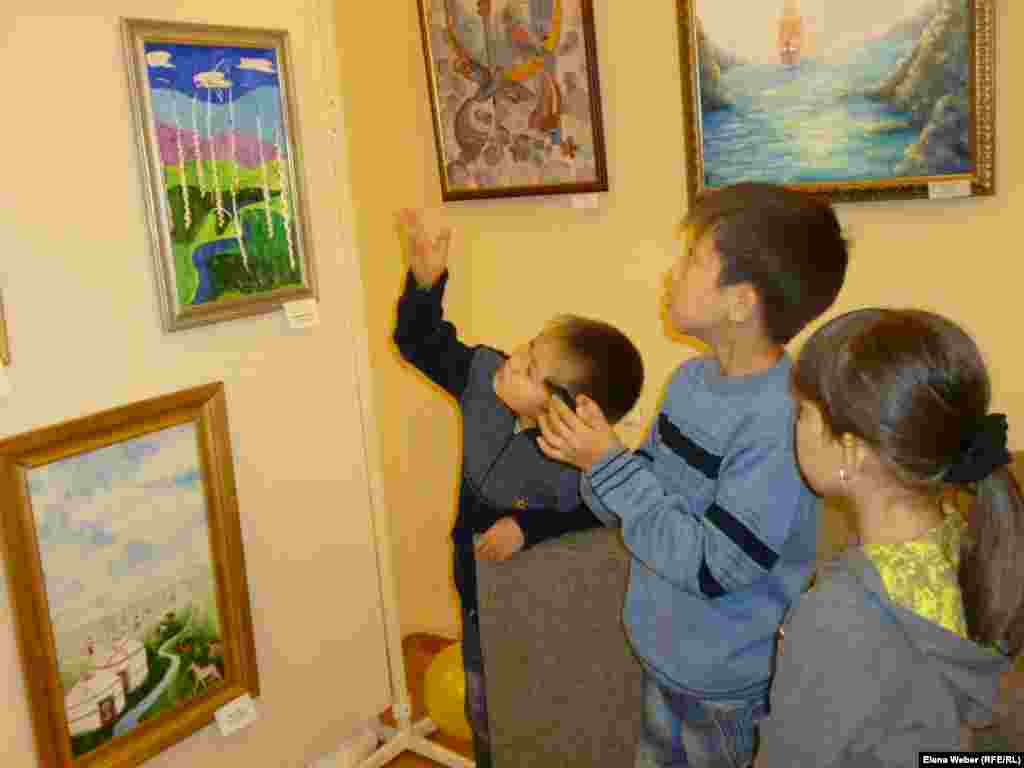 Дети рассматривают на выставке картины юных художников. &nbsp;