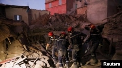 Куткаруучулар урандылардын алдынан табылган адамдын сөөгүн көтөрүп баратышат. Амизмиз шаары. Марокко. 10-сентябрь, 2023-жыл. 