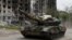 Pro-Russian troops drive a tank past a destroyed residential building in the town of Popasna in Ukraine's Luhansk region on May 26.