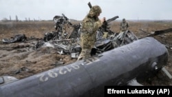 Українські військовослужбовці оглядають уламки збитого російського військового гелікоптера поблизу Макарова, що неподалік Києва, 9 квітня 2022 року