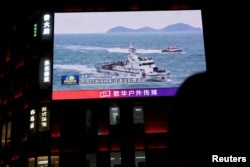 На екрані в торгівельному центрі в Пекіні видно як китайські кораблі берегової охорони патрулюють води поблизу Тайваню. Квітень 2025 року