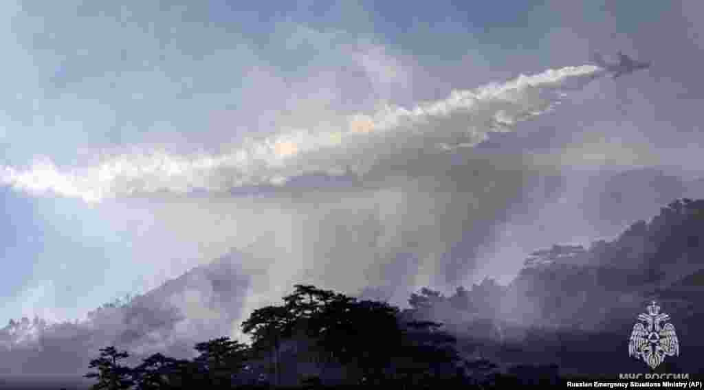 Самолет-амфибия Бе-200, направленный МЧС России, сбрасывает воду на охваченную пожаром территорию