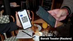 France - A woman shows a COVID-19 health pass in a cafe in Paris, August 9, 2021.
