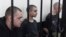 Британці Ейден Еслін (ліворуч), Шон Піннер (праворуч) та громадянин Марокко Брагім Саадун (посередині) у так званому «суді» проросійського угруповання «ДНР». Окупований Донецьк, 9 червня 2022 року 