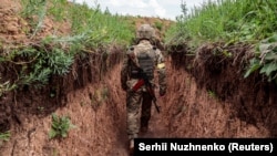 Український військовий йде в окопі на позиціях на лінії фронту, Донецька область, червень 2022 року
