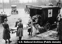 США, місто Сент-Луїс у штаті Міссурі, 1918 рік. Представники Червоного Хреста у масках винесли з будинку для подальшого транспортування жертву іспанського грипу (іспанки)
