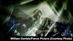 Уганда - Безгекке чалдыккан киши оорулуу бөбөгү менен дарыланбаган пашаканада отурат, William Daniels/Panos Picture