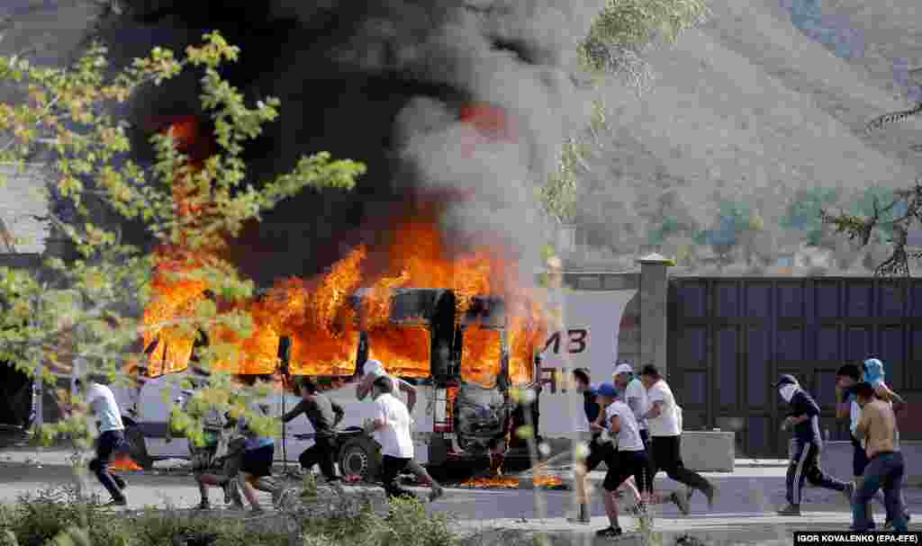 Atambaev supporters run past a flaming vehicle in Koi-Tash village.&nbsp;