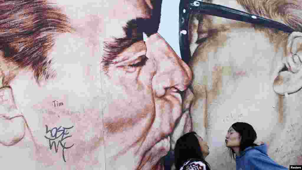 Китаянки перед Берлинской стеной с картиной Леонида Брежнева и Эрика Хонекера 3 октября, на 22-ю годовщину объединения Германии. (Reuters/Лиси Ниснер)