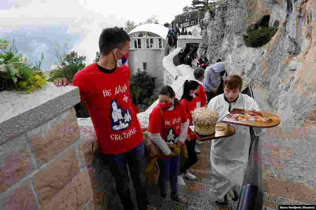 Священник спешно проходит мимо паломников к могиле святого Василия в Никшиче, Черногория. 12 мая 2020 года.&nbsp;