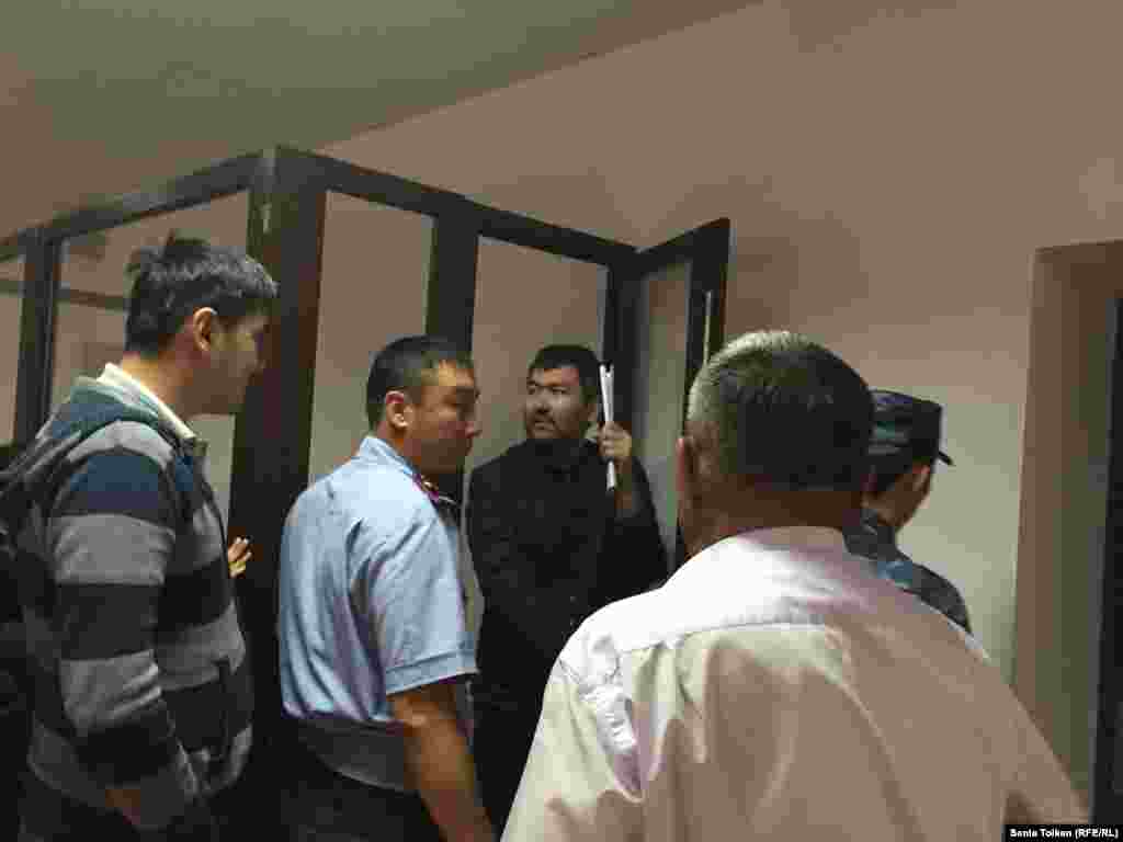 Талгат Аян выходит из отсека, где сидят арестанты в зале суда.