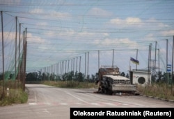 Вид на згорілий автомобіль та антидронові сітки над дорогою поблизу Добропілля на Донеччині, 10 серпня 2025 року