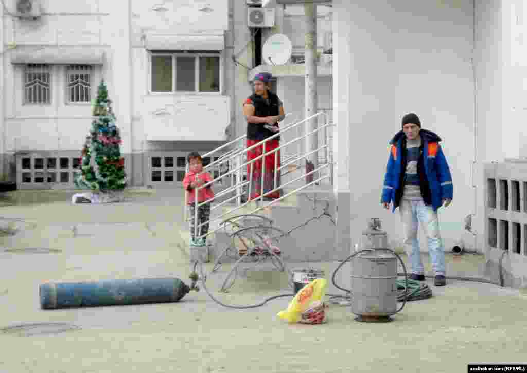 Öý hojalyk edarasynyň ýarylan turbalary bejermäge gelen işçisi.