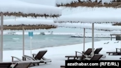 Hazar deňziniň ýakasyndaky Awaza syýahatçylyk zolagyna düşen gar plýažlarda oturdylan günden goraýjy saýawanlaryň üstüni örtdi. 24-nji fewral, 2025 ý. Awaza, Türkmenistan.