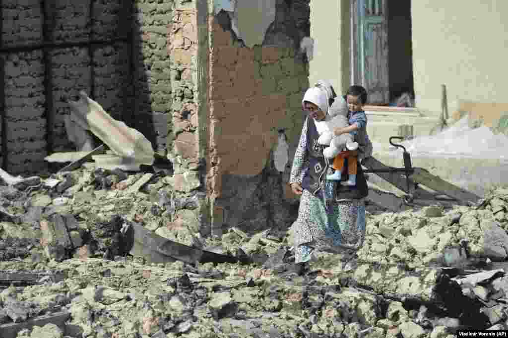 Кыргыз-тажик чек арасына жакын жайгашкан Максат айылында үйдүн урандыларын аралап жүргөн балалуу аял. 2021-жылы жазында эки өлкөнүн чек арасында куралдуу жаңжал болуп, андан ондогон адамдардын өмүрү кыйылган. Куралдуу кагылышуу он жылдап чечилбеген маселелерден келип чыкканын эки өлкө тең ырастаган. 4-май, 2021-жыл (AP Сүрөт/Владимир Воронин) &nbsp;