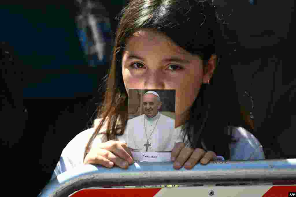 Маладая верніца трымае фота папы Францішка падчас пахавальнай цырымоніі ў цэнтры Рыму, 26 красавіка 2025 году