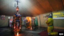 Мітингувальник молиться у наметі-капличці на майдані Незалежності, Київ, 6 січня 2014 року