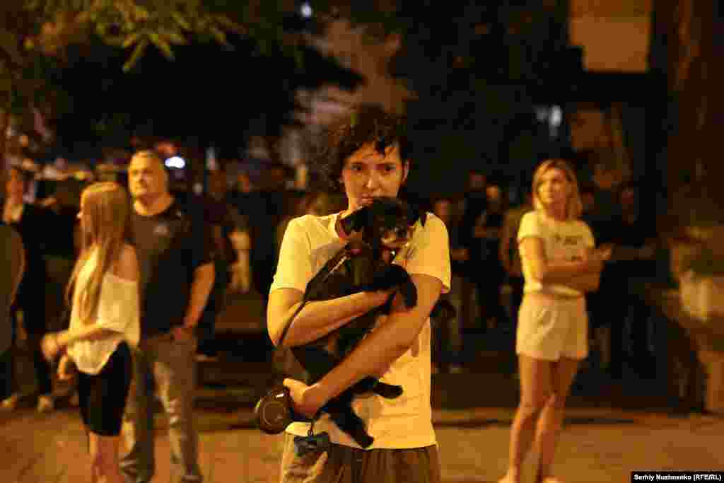 Жінка тримає свого собаку, разом з яким покинула пошкоджений російською атакою будинок