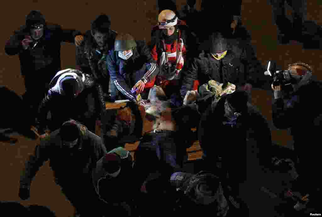 Полиция менен кагылышта жарадар болгон кишиге демонстранттар жардам берүүдө.