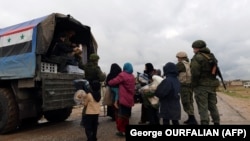SYRIA -- A Russian soldier passes out food aid to Syrian civilians as they cross from rebel-held areas in Idlib province into regime-held territories on December 27, 2018, through the Abu Duhur crossing.