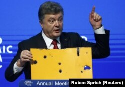 Президент України Петро Порошенко демонструє фрагмент пасажирського автобуса, який був знищений ракетним ударом російсько-сепаратистських сил на околиці Волновахи 13 січня 2015 року. Давос 21 січня 2015 року